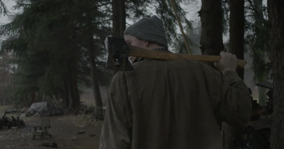 Young man stands with an ax on his shoulder