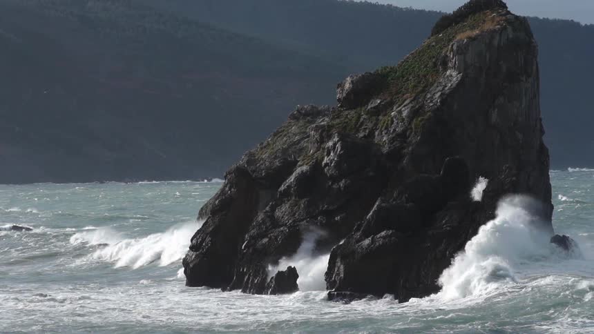 Large rock  in some water while the water flows through and around it