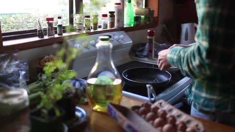 A man cracks eggs into a frying pan