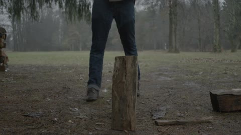 Man cuts a wood log with an axe