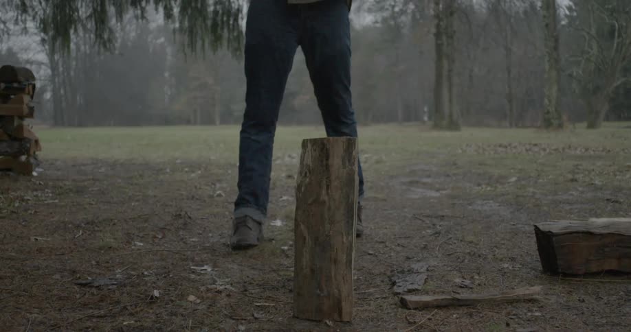 Man cuts a wood log with an axe