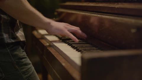A man playing an upright piano