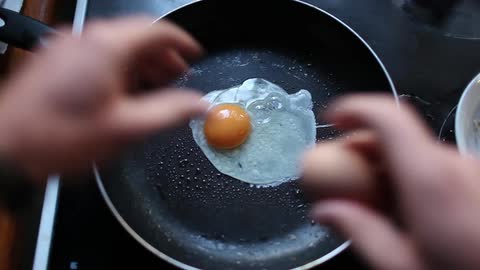 Eggs are cracked into a frying pan
