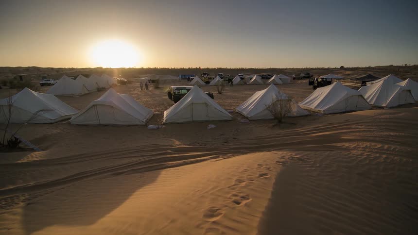 Timelapse of an encampent of white cloth tents in the desert