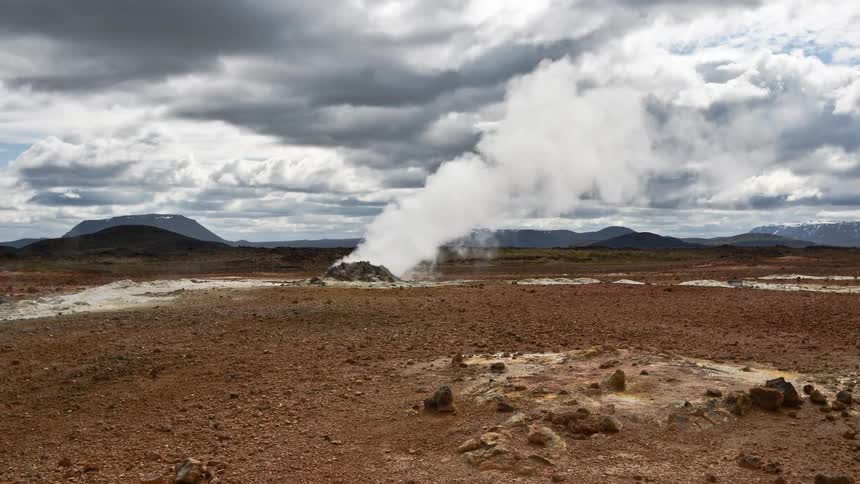 Heavy smoke rises from the ground in a desert near a canyon