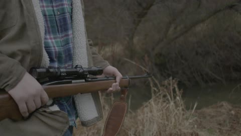 A man carries a gun outdoors