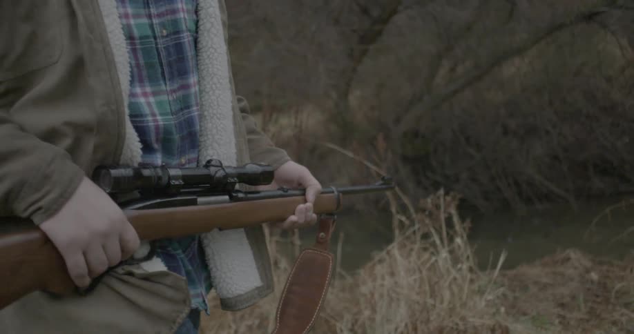 A man carries a gun outdoors