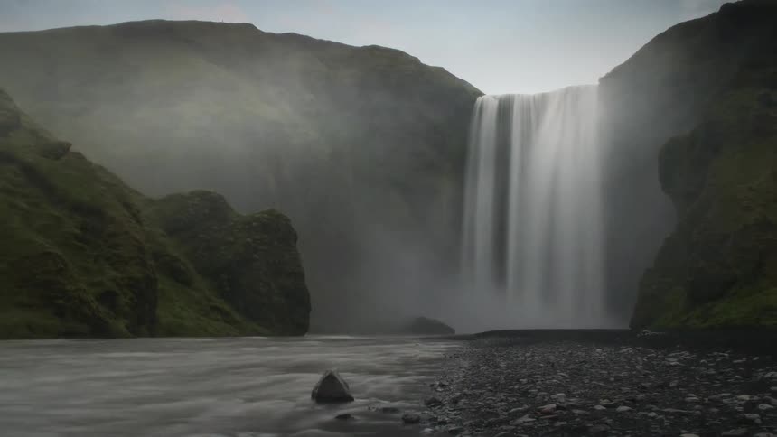 A waterfall falls from above into a river