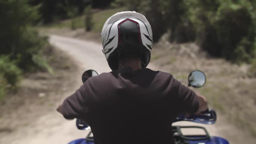 A person driving a four wheeler down a dirt road