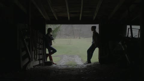 Young couple talk to each other on the door of a barn