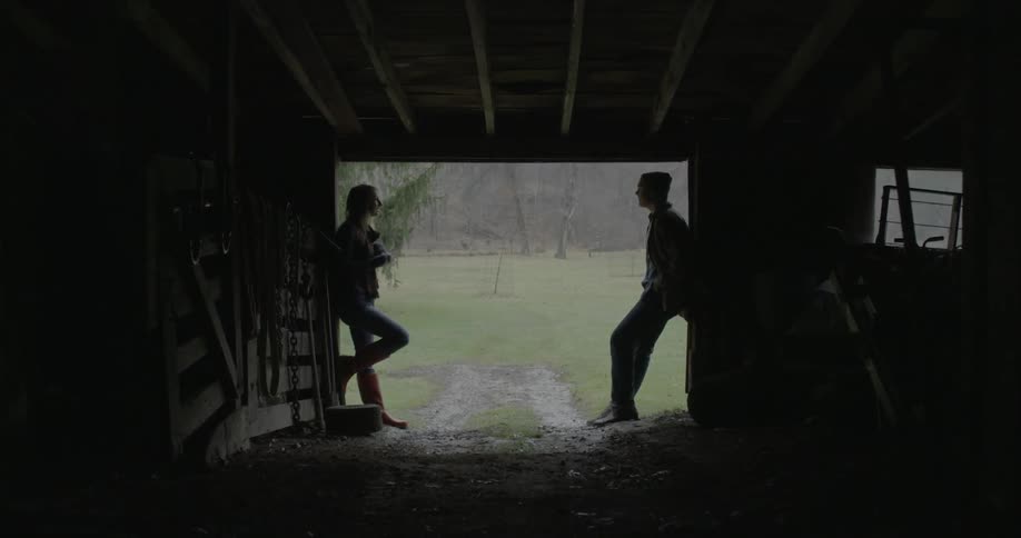 Young couple talk to each other on the door of a barn