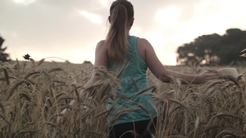 A woman walks through a grassy field