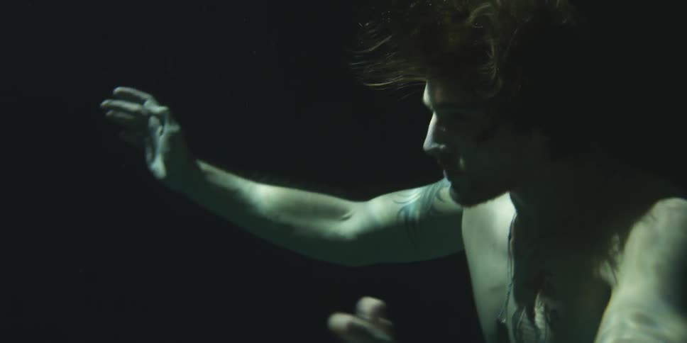 A man swimming underwater in the dark
