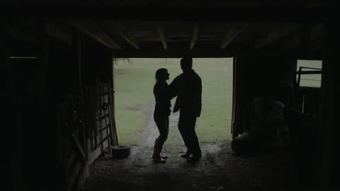 A man and woman dance inside a barn