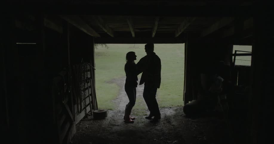 A man and woman dance inside a barn