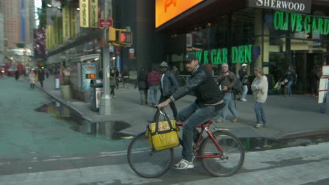 Man crossing the street in slow motion on his red bike