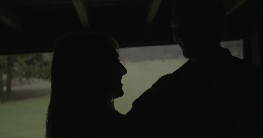 A man and a woman dancing below a shelter outside in the rain