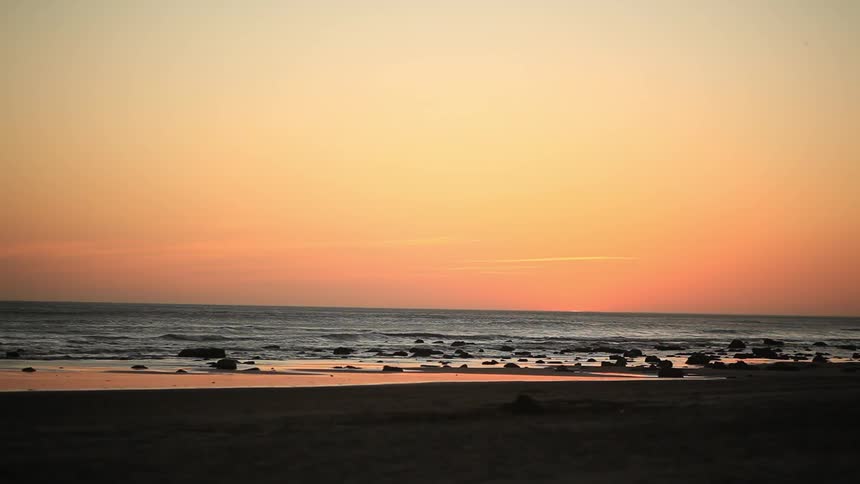 The tide goes in and out on the beach at dusk