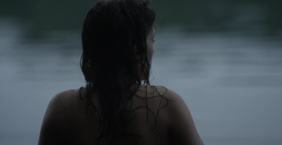 A woman with wet hair standing in front of a body of water