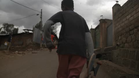 Three boys running down the road carrying skateboards