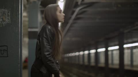A woman stands at a subway station waiting for a train