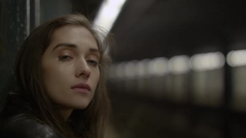 A woman stands at a subway station waiting for a train