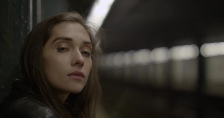 A woman stands at a subway station waiting for a train