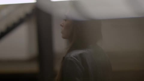 A woman stands in a train station as a train goes by