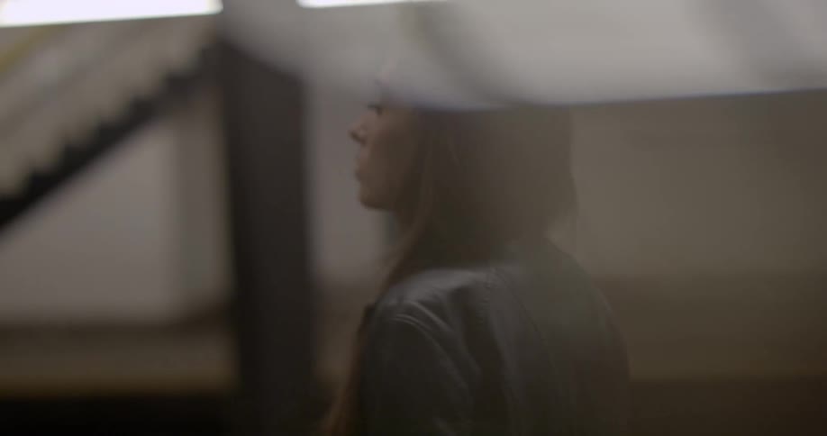 A woman stands in a train station as a train goes by
