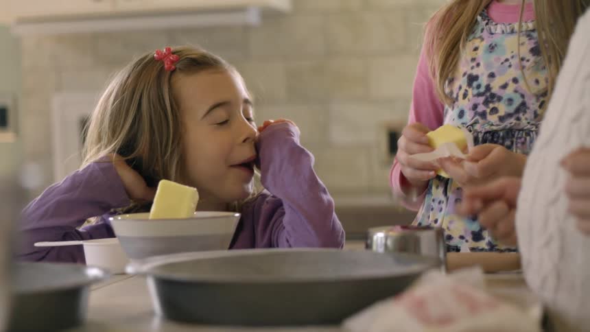 Girl and family bake in kitchen with butter