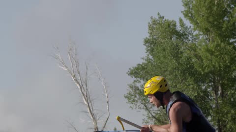 A man is sitting on some type of water ski and being pulled through the water when he makes a full turn in the air