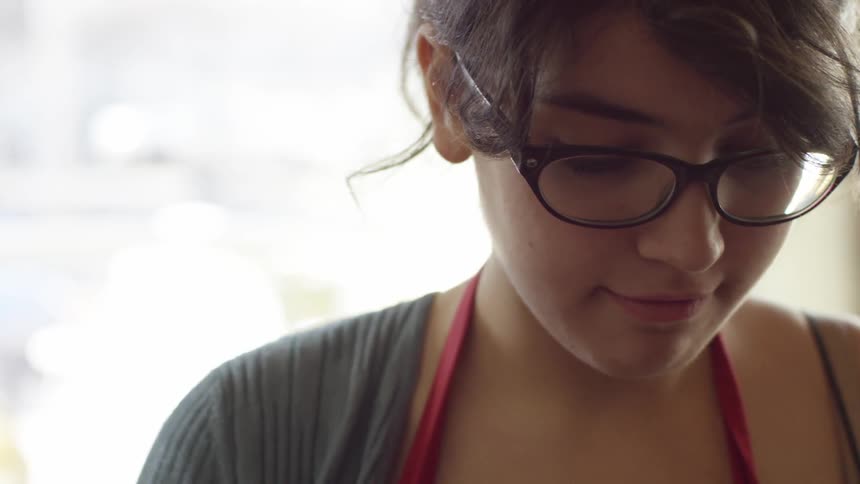 Woman wearing glasses looks down and smiles