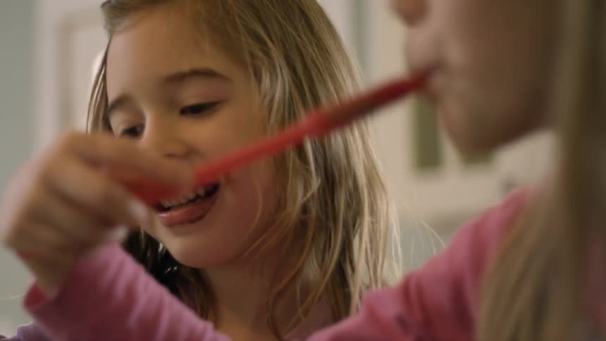 Two girls eat from a spoon