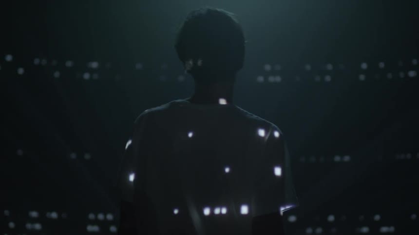 Lights are projected onto a man and wall
