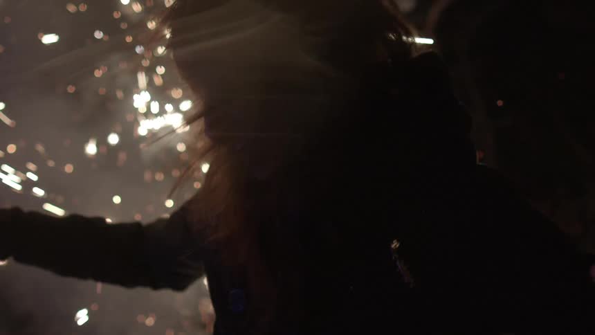 A woman is dancing amongst fireworks