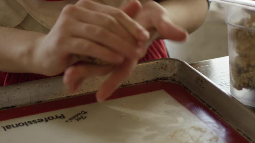 A woman is shaping cookie dough for a small bakery