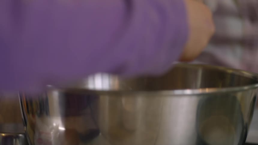 Woman teaching kids how to crack and egg on a metal bowl