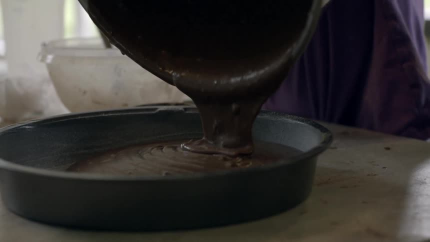 Chocolate batter is poured into a cake pan