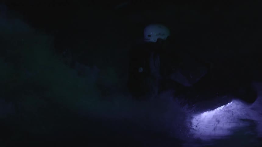 A lighted kayak travels through rough water at night