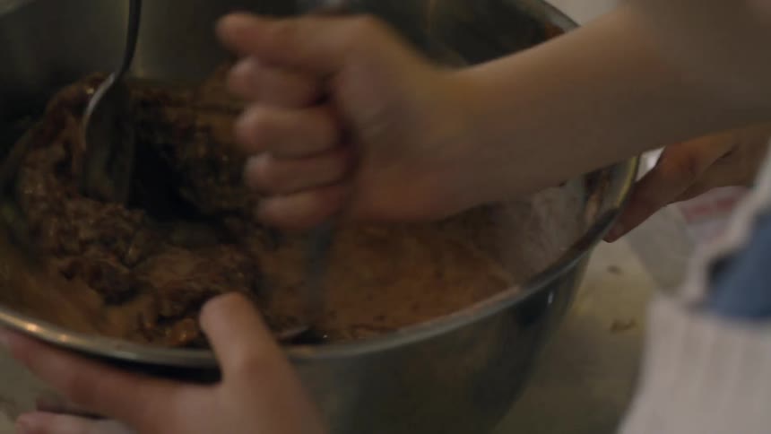 Spoons are used to stir a bowl of baking ingredients