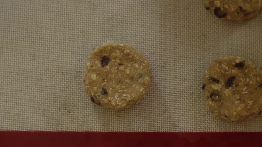 A person places unbaked cookie dough on a baking sheet