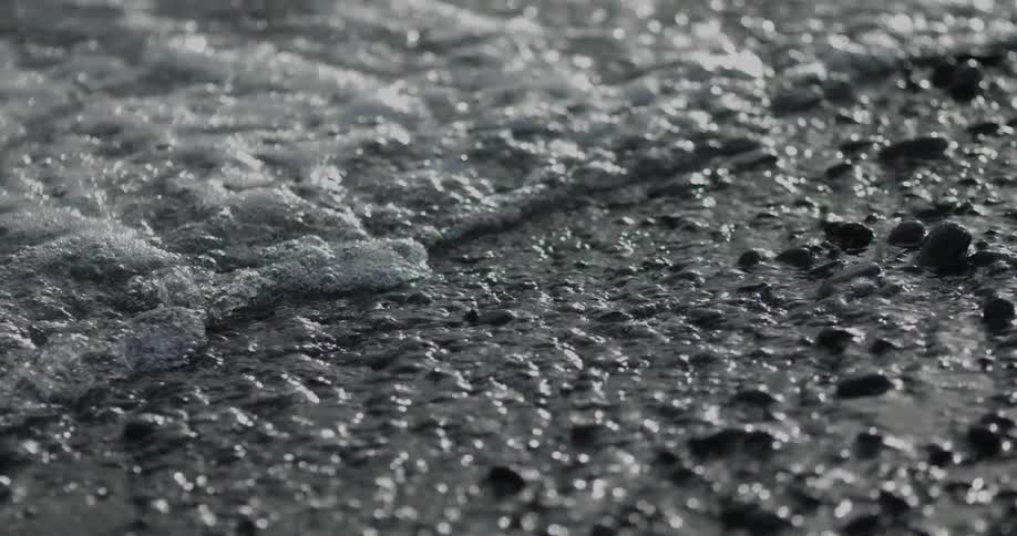 The tide of the ocean rolling in over rocky sand