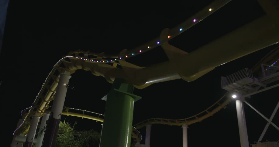 A roller coaster moves along a track at night
