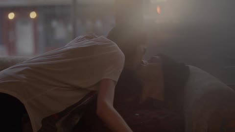 A woman kisses a man sitting on a sofa