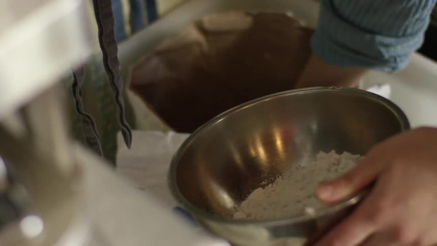 A person pouring flower into a bowl