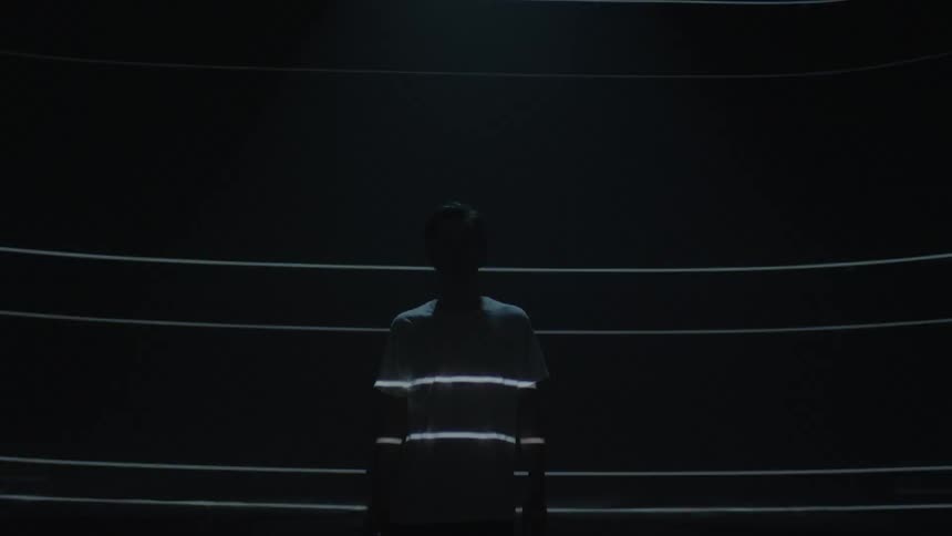 Lights shine on a man and the wall behind him