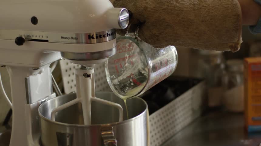 Melted butter being poured into metal bowl of an electric mixer