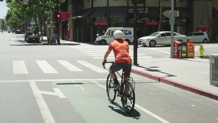 A person riding a bike down a city street on a sunny day