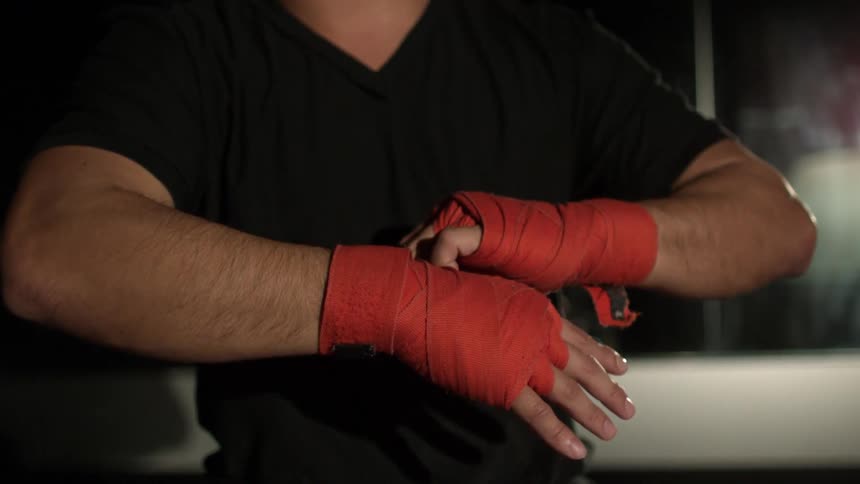 A man putting on red weight lifting gloves