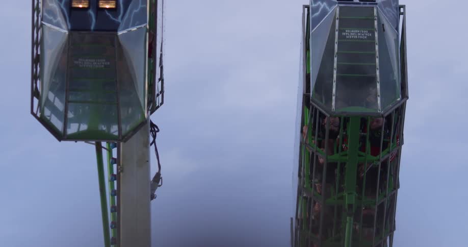 An amusement park ride and flags in the cloudy sky